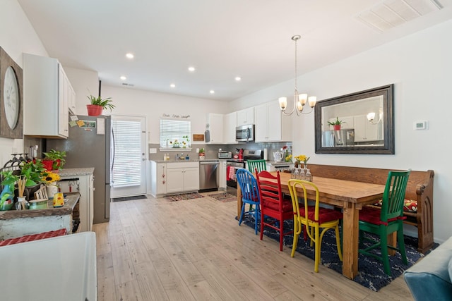 dining area with light wood-style flooring, a chandelier, and recessed lighting