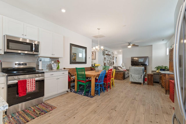 kitchen with stainless steel appliances, light wood-style floors, white cabinets, ceiling fan, and backsplash