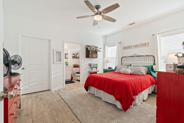 bedroom with light wood-style flooring, a ceiling fan, and connected bathroom