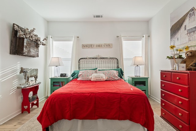 bedroom with multiple windows, light wood-type flooring, and baseboards