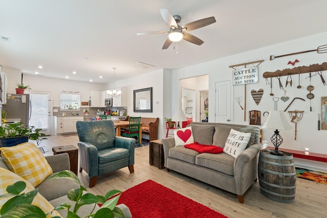 living room with a chandelier, light wood-type flooring, a ceiling fan, and recessed lighting