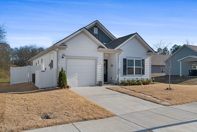single story home featuring an attached garage, board and batten siding, driveway, fence, and central AC