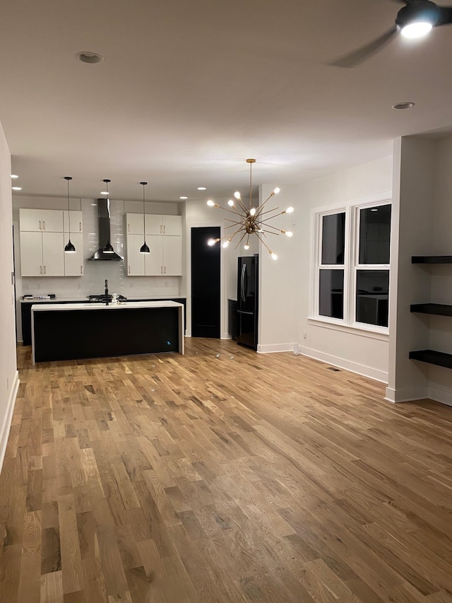 unfurnished living room with light wood-style floors, ceiling fan, baseboards, a chandelier, and recessed lighting