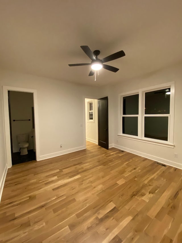 unfurnished room with baseboards, a ceiling fan, and light wood-style flooring