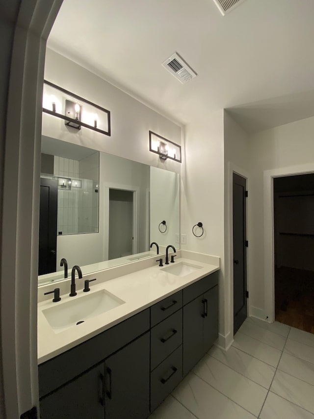 full bath featuring tiled shower, double vanity, and marble finish floors