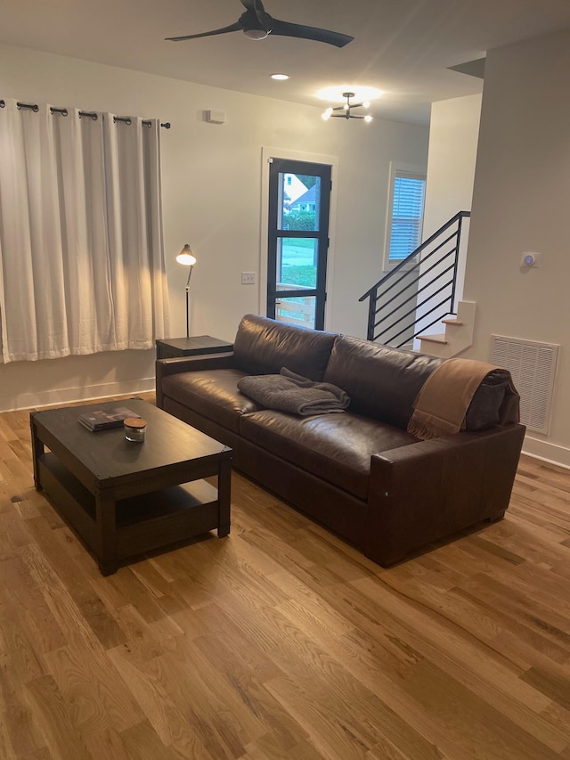 living area with ceiling fan, wood finished floors, and stairway