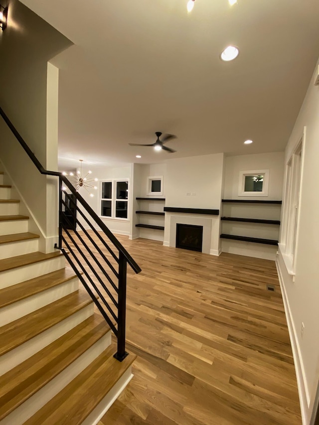unfurnished living room with wood finished floors, stairs, recessed lighting, ceiling fan, and baseboards
