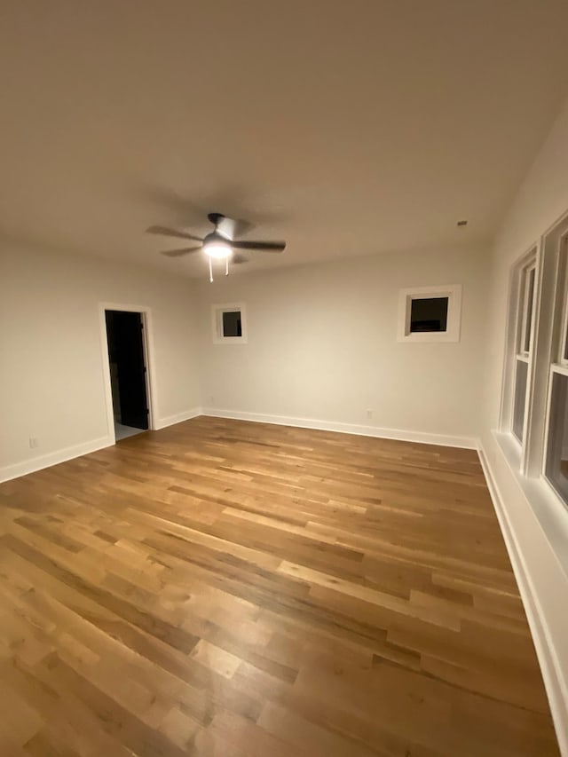 empty room featuring wood finished floors, ceiling fan, and baseboards
