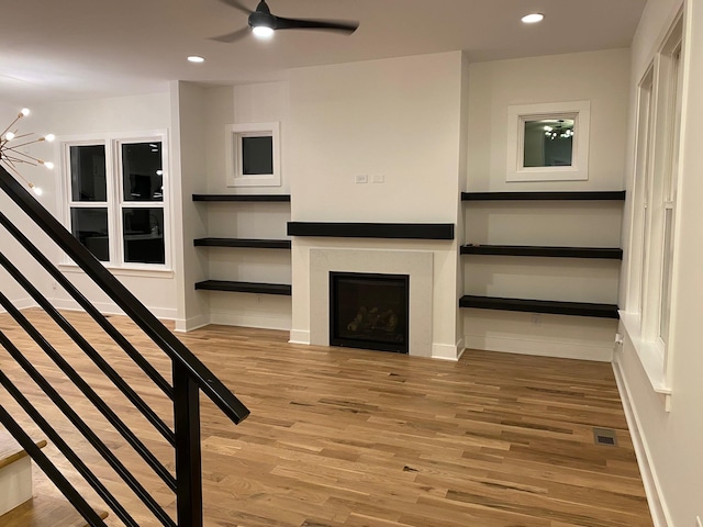 unfurnished living room with wood finished floors, a fireplace, a ceiling fan, recessed lighting, and stairway