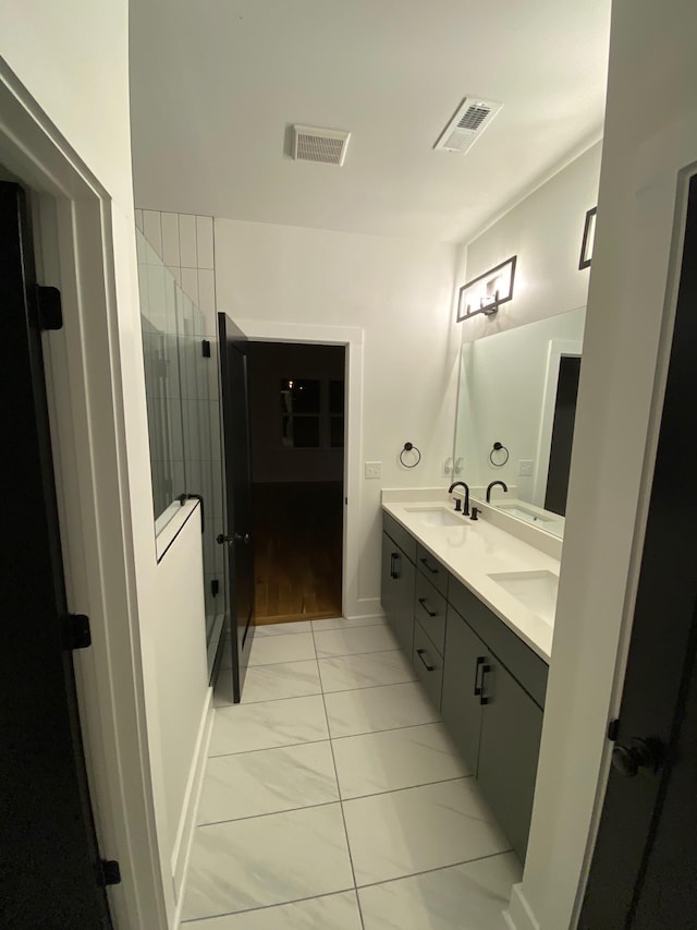 bathroom with marble look tile flooring, double vanity, and a tile shower