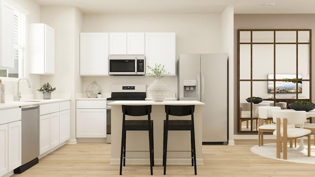 kitchen featuring appliances with stainless steel finishes, a sink, light wood-style flooring, white cabinets, and a kitchen bar
