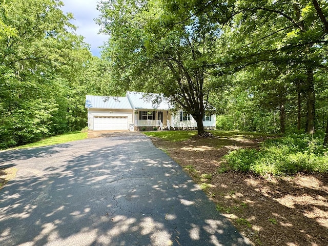 130 Jordan Ln, Hohenwald, TN 38462 - view of front of property featuring driveway, a porch, a garage, metal roof, and a wooded view