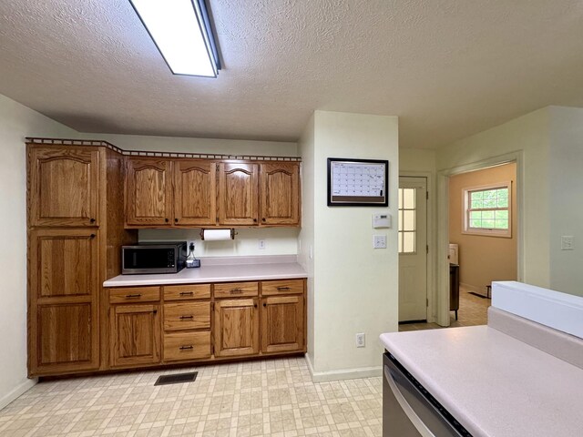 130 Jordan Ln, Hohenwald, TN 38462 - kitchen featuring stainless steel microwave, light countertops, brown cabinets, a textured ceiling, and baseboards