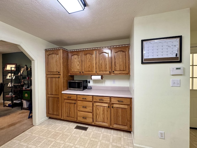 130 Jordan Ln, Hohenwald, TN 38462 - kitchen featuring stainless steel microwave, brown cabinets, light countertops, a textured ceiling, and baseboards