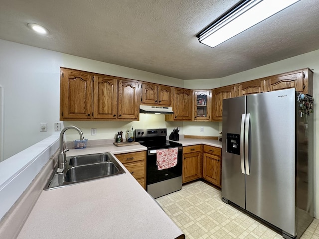 130 Jordan Ln, Hohenwald, TN 38462 - kitchen with stainless steel appliances, under cabinet range hood, a sink, brown cabinetry, and light floors