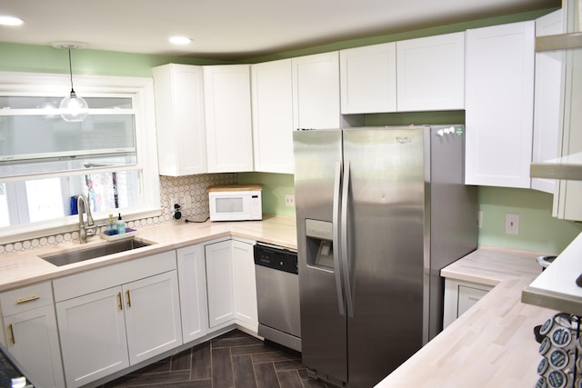 kitchen with appliances with stainless steel finishes, a sink, recessed lighting, white cabinetry, and pendant lighting
