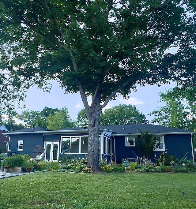 view of front of house with a front lawn, french doors, and a sunroom