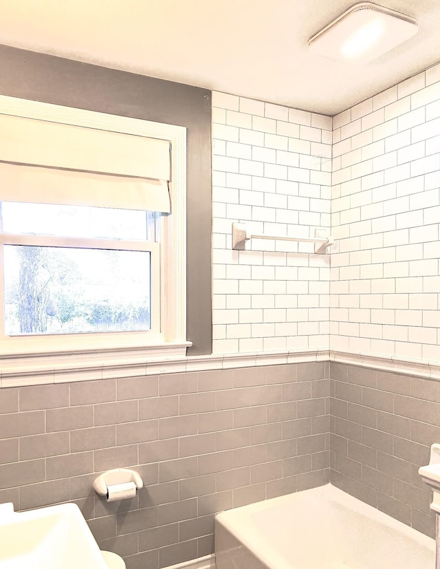 full bath featuring tile walls and a sink