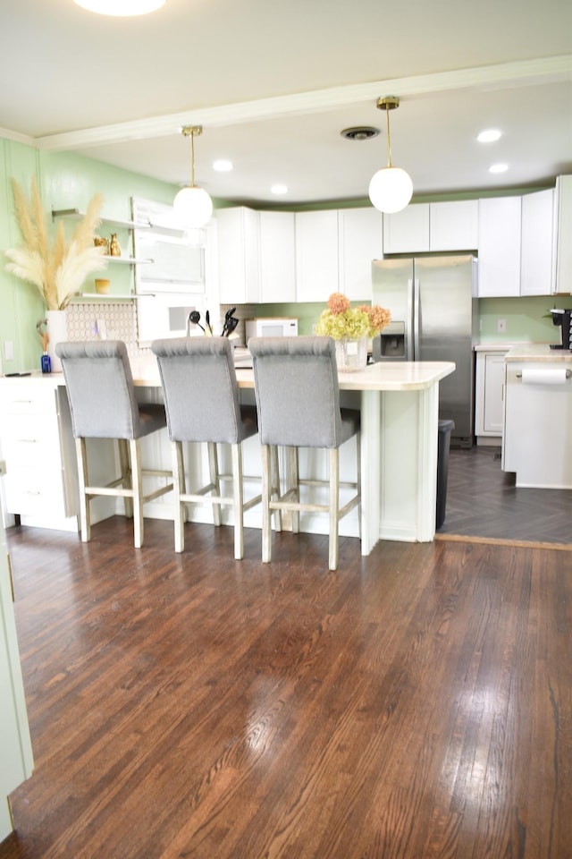 kitchen featuring stainless steel refrigerator with ice dispenser, white cabinets, hanging light fixtures, dark wood-style floors, and recessed lighting