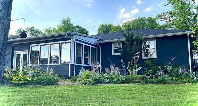 view of property exterior with a sunroom, a yard, and brick siding