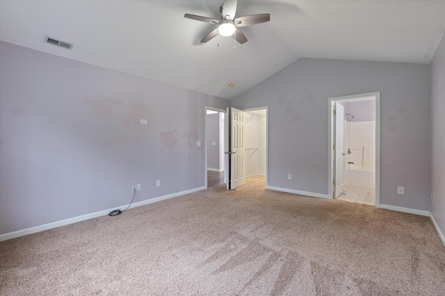 unfurnished bedroom featuring carpet, vaulted ceiling, a walk in closet, baseboards, and connected bathroom