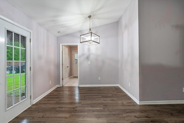 unfurnished dining area featuring healthy amount of natural light, a chandelier, wood finished floors, and vaulted ceiling