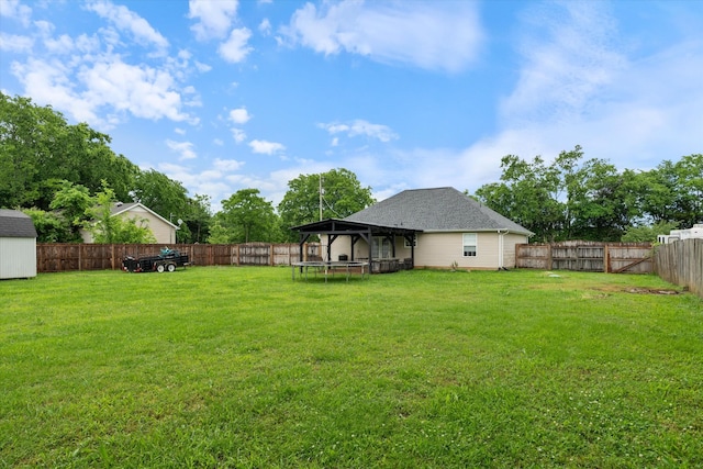 view of yard with a trampoline, a gazebo, a shed, and an outbuilding