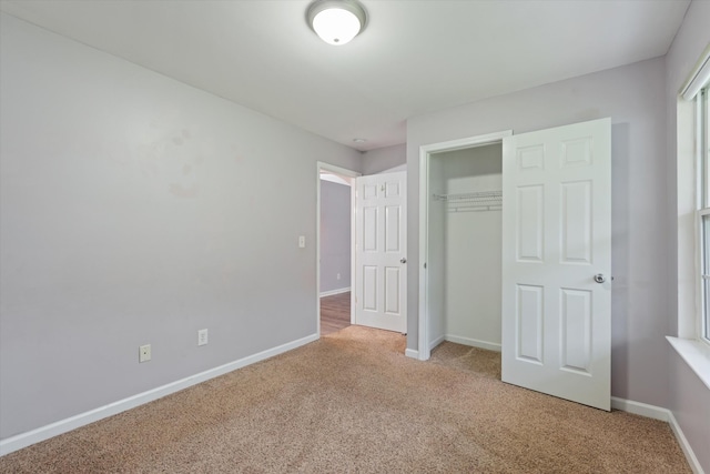unfurnished bedroom with light carpet, baseboards, and a closet