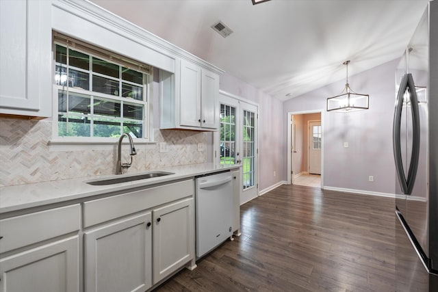 kitchen featuring a sink, stainless steel refrigerator, white dishwasher, tasteful backsplash, and vaulted ceiling