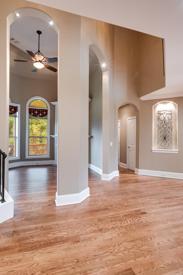 291 Bowling Branch Rd, Cottontown, TN 37048 - unfurnished living room featuring ceiling fan, light wood-style flooring, arched walkways, baseboards, and a high ceiling