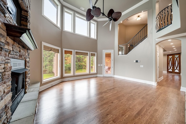 291 Bowling Branch Rd, Cottontown, TN 37048 - unfurnished living room featuring a ceiling fan, a stone fireplace, arched walkways, crown molding, and a towering ceiling