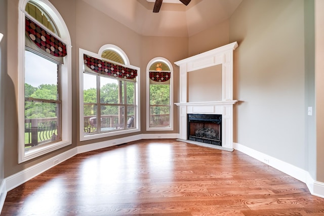 291 Bowling Branch Rd, Cottontown, TN 37048 - unfurnished living room featuring a ceiling fan, a fireplace with flush hearth, wood finished floors, baseboards, and a towering ceiling