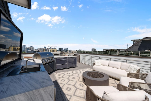 view of patio featuring an outdoor living space with a fire pit, exterior kitchen, a view of city, and a grill