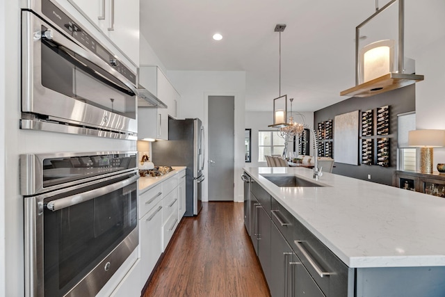 kitchen with dark wood-type flooring, a sink, white cabinetry, hanging light fixtures, and recessed lighting