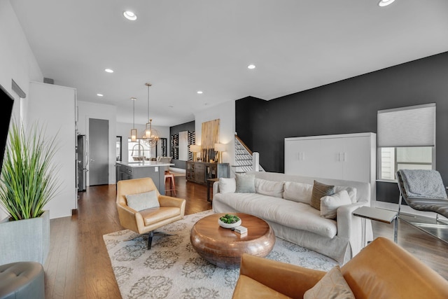 living area with a chandelier, recessed lighting, dark wood-style flooring, and stairway