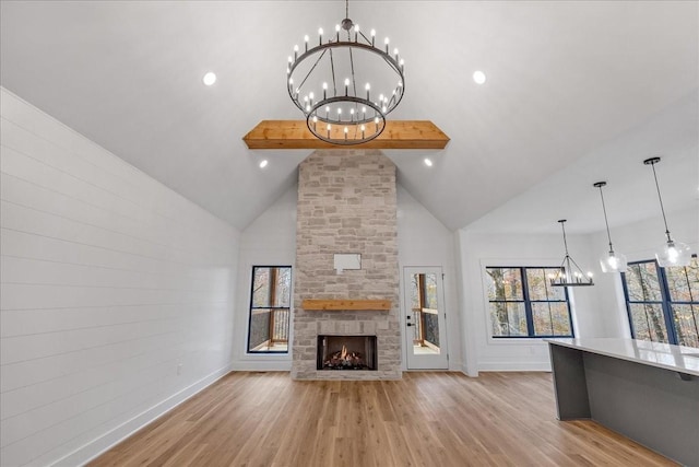 113 Lake Crest Ln, Tullahoma, TN 37388 - unfurnished living room featuring a chandelier, baseboards, light wood-style flooring, a stone fireplace, and beam ceiling