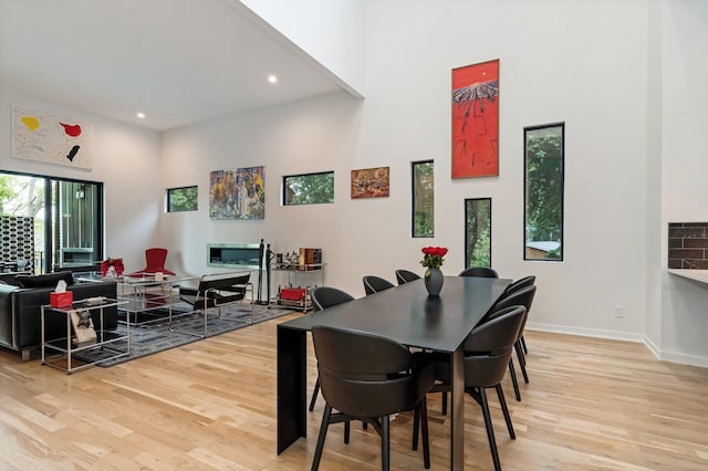 dining room with a high ceiling, light wood-type flooring, recessed lighting, and baseboards