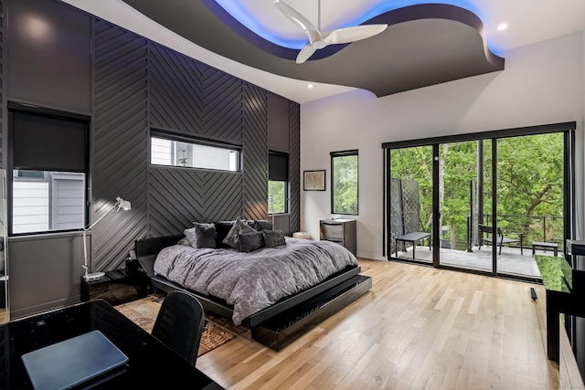 bedroom featuring access to outside, recessed lighting, an accent wall, light wood-style floors, and multiple windows