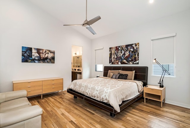 bedroom with light wood-style floors, vaulted ceiling, ensuite bath, baseboards, and a ceiling fan