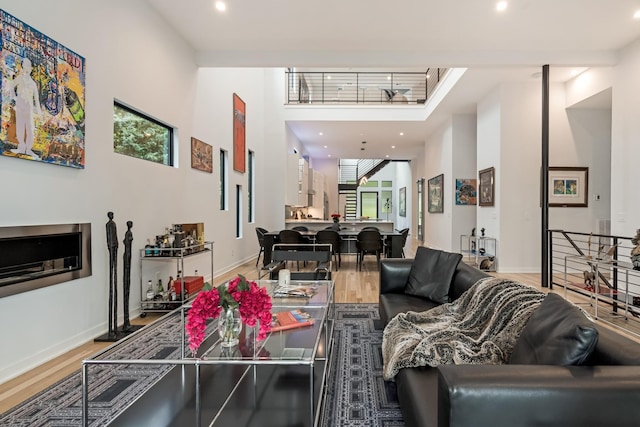 living room with wood finished floors, a high ceiling, recessed lighting, and baseboards