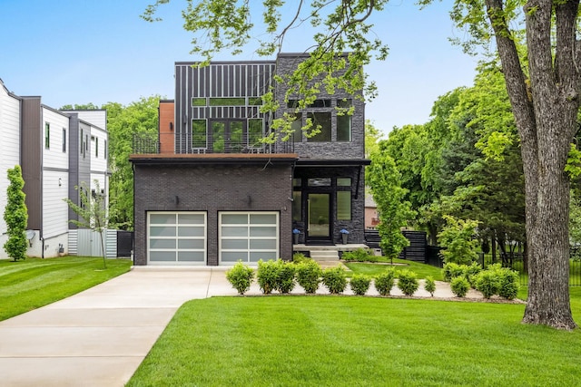 contemporary home featuring driveway, a garage, a front yard, brick siding, and a balcony