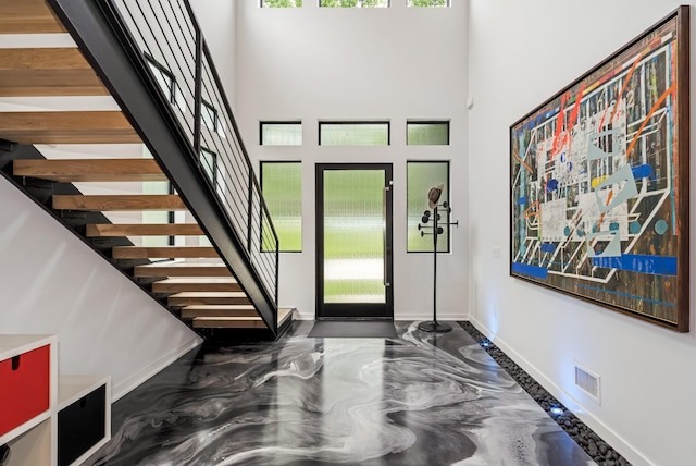 entryway with plenty of natural light, baseboards, stairway, and a high ceiling