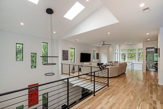 living room featuring recessed lighting, light wood finished floors, a skylight, and high vaulted ceiling