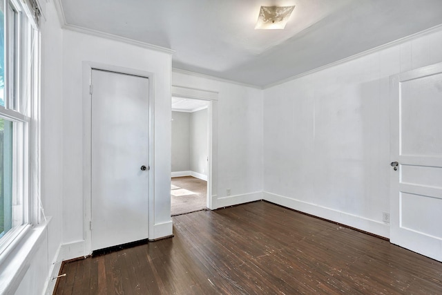 empty room with crown molding, dark wood-style floors, and baseboards