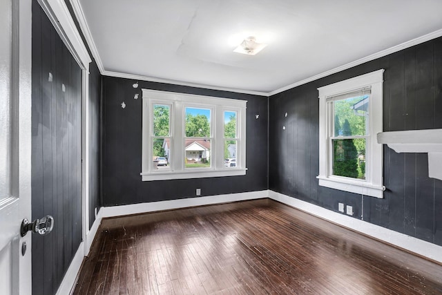 unfurnished room featuring wood-type flooring, ornamental molding, and baseboards