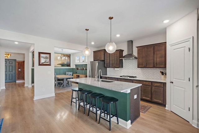 1125 Clendening Dr, Gallatin, TN 37066 - kitchen featuring wall chimney range hood, stainless steel appliances, dark brown cabinets, a kitchen bar, and an island with sink
