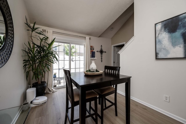 dining room with vaulted ceiling, wood finished floors, and baseboards
