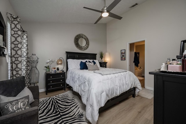 bedroom with vaulted ceiling, light wood finished floors, baseboards, a textured ceiling, and a ceiling fan