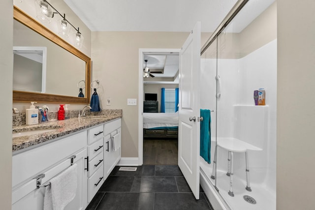 ensuite bathroom with a shower stall, a ceiling fan, double vanity, and tile patterned floors