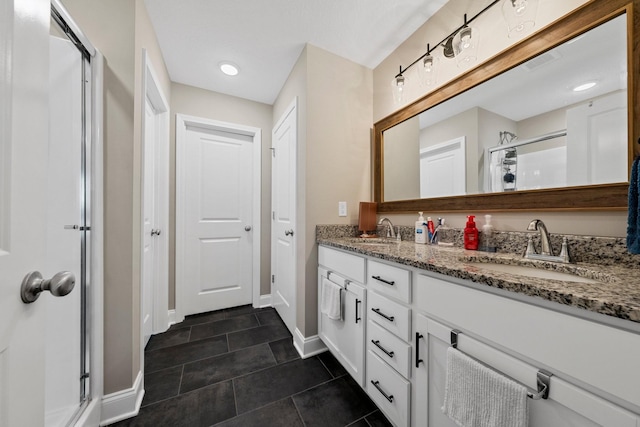 bathroom with a stall shower, tile patterned floors, double vanity, and baseboards